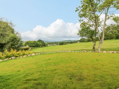 A grassy field with trees and stones in the background at The Lodge in Blairgowrie