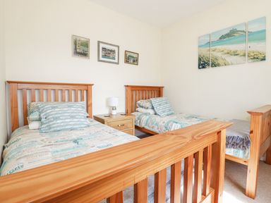 A bedroom with two single wooden beds and a bedside table with a lamp at 2 Old Talbot Cottages in Lostwithiel