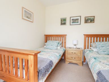 A bedroom with two single wooden beds and a wooden nightstand between them at 2 Old Talbot Cottages in Lostwithiel