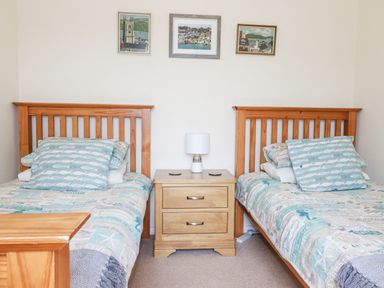 A bedroom with two single wooden beds and a wooden nightstand between them at 2 Old Talbot Cottages in Lostwithiel