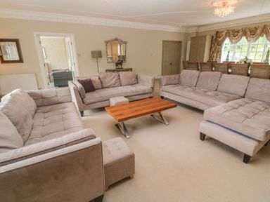 A living room with three sofas a wooden coffee table and a dining table with chairs at Bodmin Country House in Lanivet