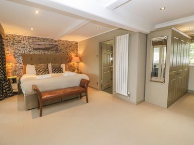 A bedroom with a large bed two lamps a bench a mirror and a wardrobe at Bodmin Country House in Lanivet