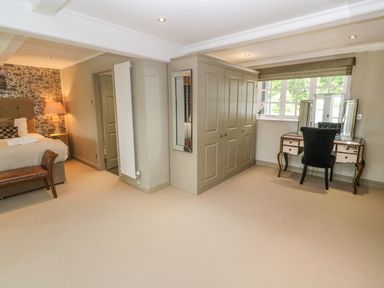 A bedroom with a bed a bench wardrobe and a dressing table with a chair at Bodmin Country House in Lanivet