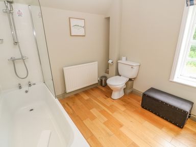 A bathroom with a bathtub shower toilet radiator and a storage bench at Bodmin Country House in Lanivet