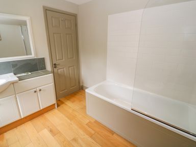 A bathroom with a bathtub a vanity unit with a sink a mirror and a closed door at Bodmin Country House Lanivet