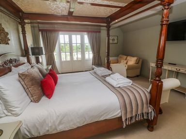 A bedroom with a four poster bed pillows towels and a sofa near a window at Bodmin Country House Lanivet