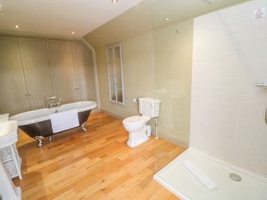 A bathroom with a clawfoot bathtub toilet shower and wooden floor at Bodmin Country House in Lanivet