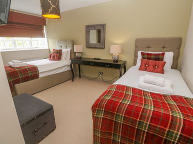 A bedroom with two single beds a black desk with lamps a mirror and a window at Bodmin Country House in Lanivet