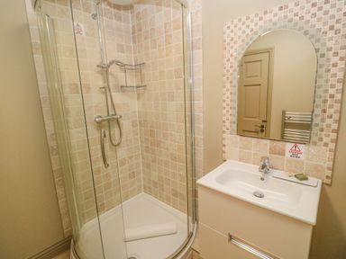 A bathroom with a glass shower enclosure and a white sink with a mirror at Bodmin Country House in Lanivet