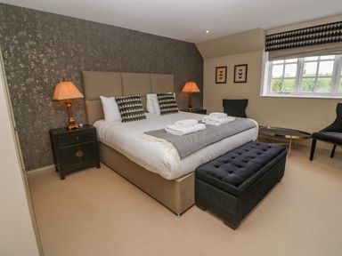 A bedroom with a large bed two nightstands with lamps two chairs and a window at Bodmin Country House in Lanivet