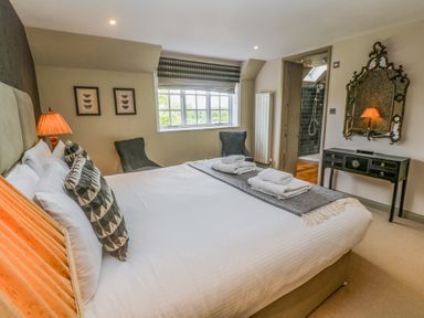 A bedroom with a bed table lamp two chairs and a mirror at Bodmin Country House in Lanivet