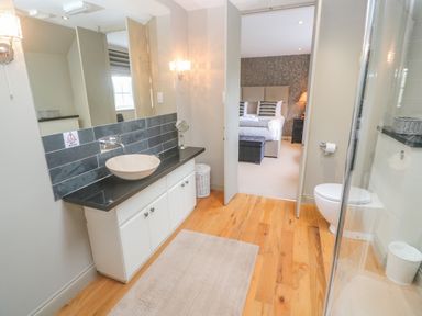 A bathroom with a sink countertop toilet shower and an open door leading to a bedroom at Bodmin Country House Lanivet