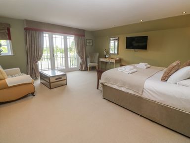 A bedroom with a bed and a wall-mounted TV at Bodmin Country House in Lanivet