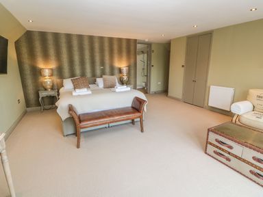 A bedroom with a double bed two bedside lamps a leather bench a chair and a suitcase style chest at Bodmin Country House Lanivet
