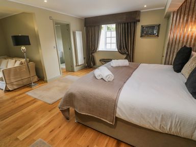 A bedroom with a bed and rolled towels with a window and curtains at Bodmin Country House in Lanivet
