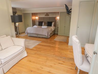 A bedroom with a bed, wardrobe, chair, desk, lamp, and sofa at Bodmin Country House in Lanivet