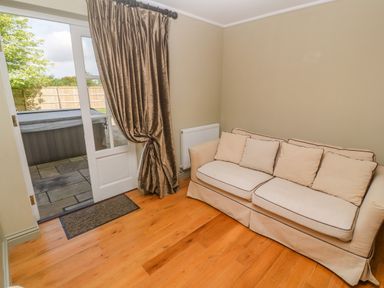 A room with a beige sofa wooden floor and door leading outside at Bodmin Country House in Lanivet