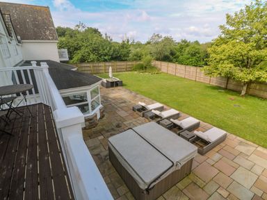 A backyard with a hot tub patio chairs and a table with umbrella enclosed by a wooden fence at Bodmin Country House in Lanivet