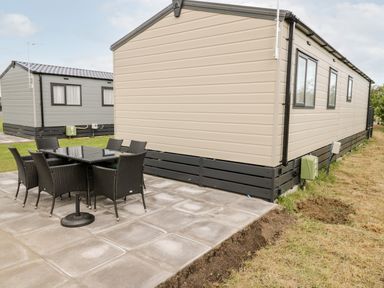 Outdoor patio area with a dining table and six chairs beside two mobile homes at Lazy Daze Carnaby near Bridlington