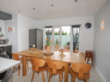 A dining area with a wooden table and chairs near glass doors leading outside at The Old Coal Yard in Cemaes Bay