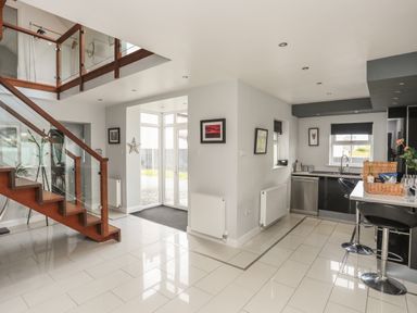 An open area with a wooden staircase and a kitchen with bar stools at The Old Coal Yard in Cemaes Bay