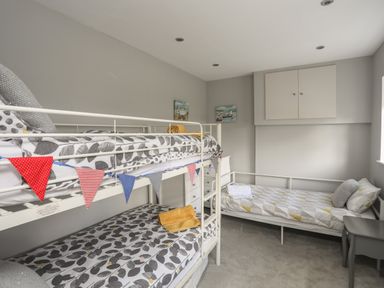A bedroom with a bunk bed and a single bed with towels on each at The Old Coal Yard in Cemaes Bay