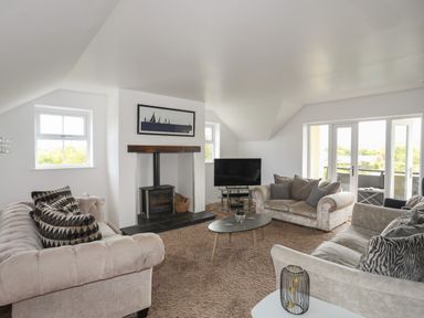 A living room with sofas coffee table television and wood burner at The Old Coal Yard in Cemaes Bay