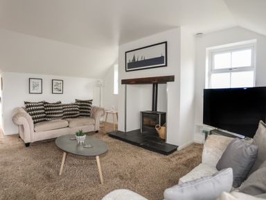 A living room with sofas a coffee table a fireplace and a television at The Old Coal Yard in Cemaes Bay