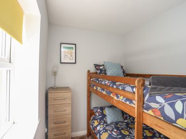 A bedroom with wooden bunk beds a chest of drawers and a framed picture on the wall at The Old Coal Yard in Cemaes Bay