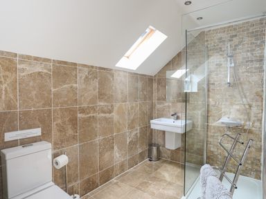 A bathroom with a toilet sink glass shower and skylight window at The Old Coal Yard in Cemaes Bay