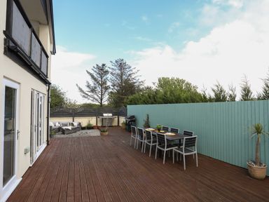 An outdoor patio with a dining table and chairs a barbecue and seating area at The Old Coal Yard in Cemaes Bay