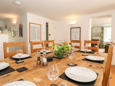 A dining room with a wooden table set with plates napkins and wine glasses and a flower centerpiece at Huntingstile Lodge in Grasmere
