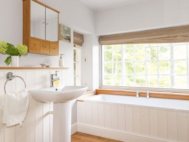 A bathroom with a pedestal sink a bathtub and a large window at Huntingstile Lodge in Grasmere