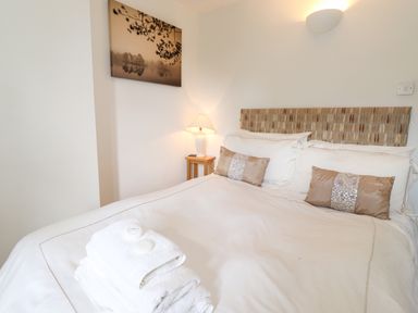 A bedroom with a bed with pillows a bedside table with a lamp and folded towels on the bed at Huntingstile Lodge in Grasmere