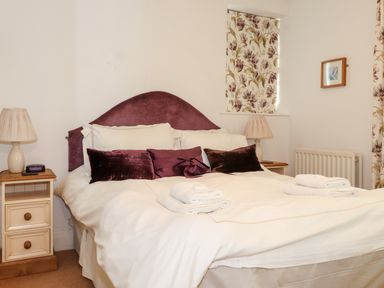 A bedroom with a double bed two bedside tables lamps floral curtains and folded towels on the bed at Huntingstile Lodge in Grasmere