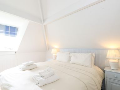 A bedroom with a double bed lamps on bedside tables and folded towels on the bed at Huntingstile Lodge in Grasmere