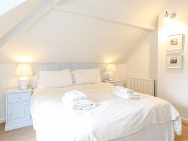 A bedroom with a double bed two bedside tables with lamps and folded towels on the bed at Huntingstile Lodge in Grasmere