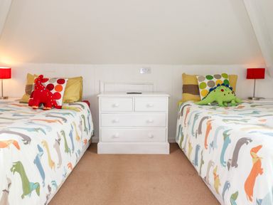 A bedroom with two single beds a white chest of drawers and red lamps at Huntingstile Lodge in Grasmere