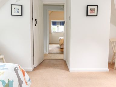 A hallway with an open door leading to a bedroom with a window and a bed at Huntingstile Lodge in Grasmere