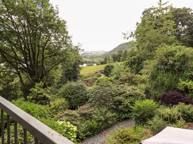 A garden with trees shrubs and flowers viewed from a balcony at Huntingstile Lodge in Grasmere