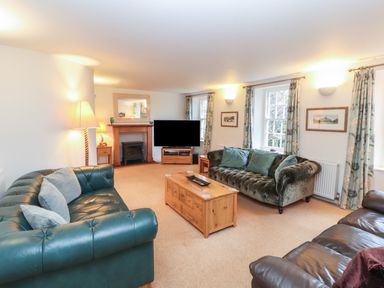 A living room with sofas, a coffee table, a television, and a fireplace at Huntingstile Lodge in Grasmere