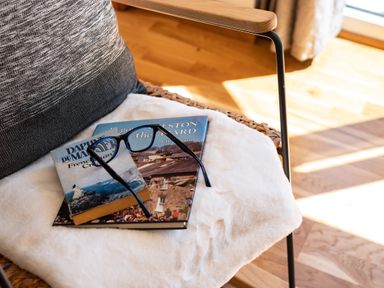 A chair with a cushion books and reading glasses placed on it at Chi Lowarth in Porthleven