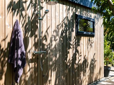 An outdoor shower with a towel hanging on a wooden wall at Chi Lowarth in Porthleven