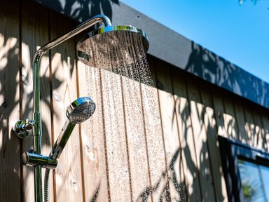 An outdoor shower with water running mounted on a wooden wall under a blue sky at Chi Lowarth in Porthleven