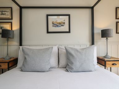 A bedroom with a bed with two gray pillows and two bedside tables with lamps at Chi Lowarth in Porthleven