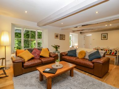 A living room with two leather sofas a wooden coffee table and a window at Pentre Court Cottage in Abergavenny