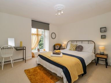 A bedroom with a double bed and bedside tables with lamps at Pentre Court Cottage in Abergavenny