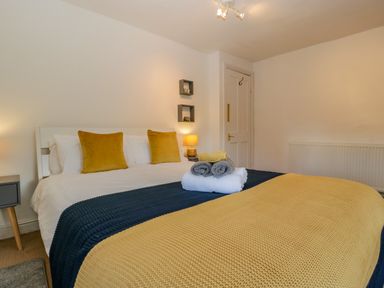 A bedroom with a bed with yellow and gray towels and pillows at Pentre Court Cottage in Abergavenny