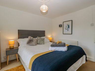 A bedroom with a double bed bedside tables with lamps and a framed picture at Pentre Court Cottage in Abergavenny
