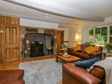 A living room with leather sofas and a wooden coffee table near a fireplace at Pentre Court Cottage in Abergavenny